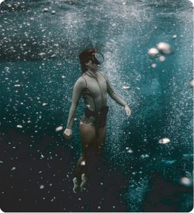 A guest floating underwater surrounded by rising bubbles