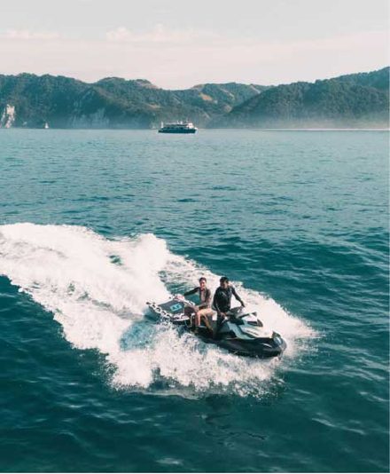 Two guests riding a jet ski across calm ocean water
