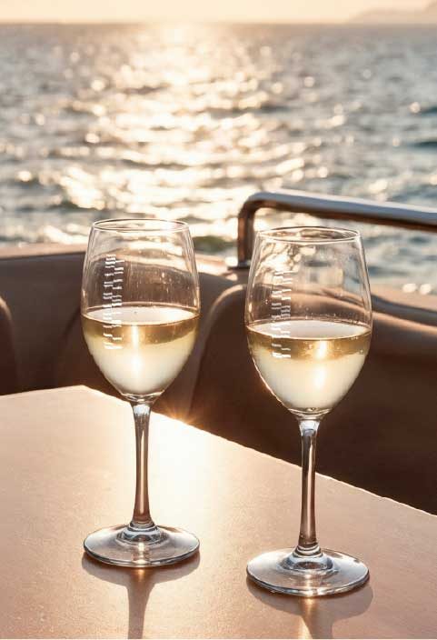 Two wine glasses catching sunset light on the yacht deck