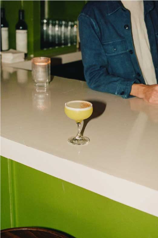 A cocktail on a pale bar counter in warm evening light