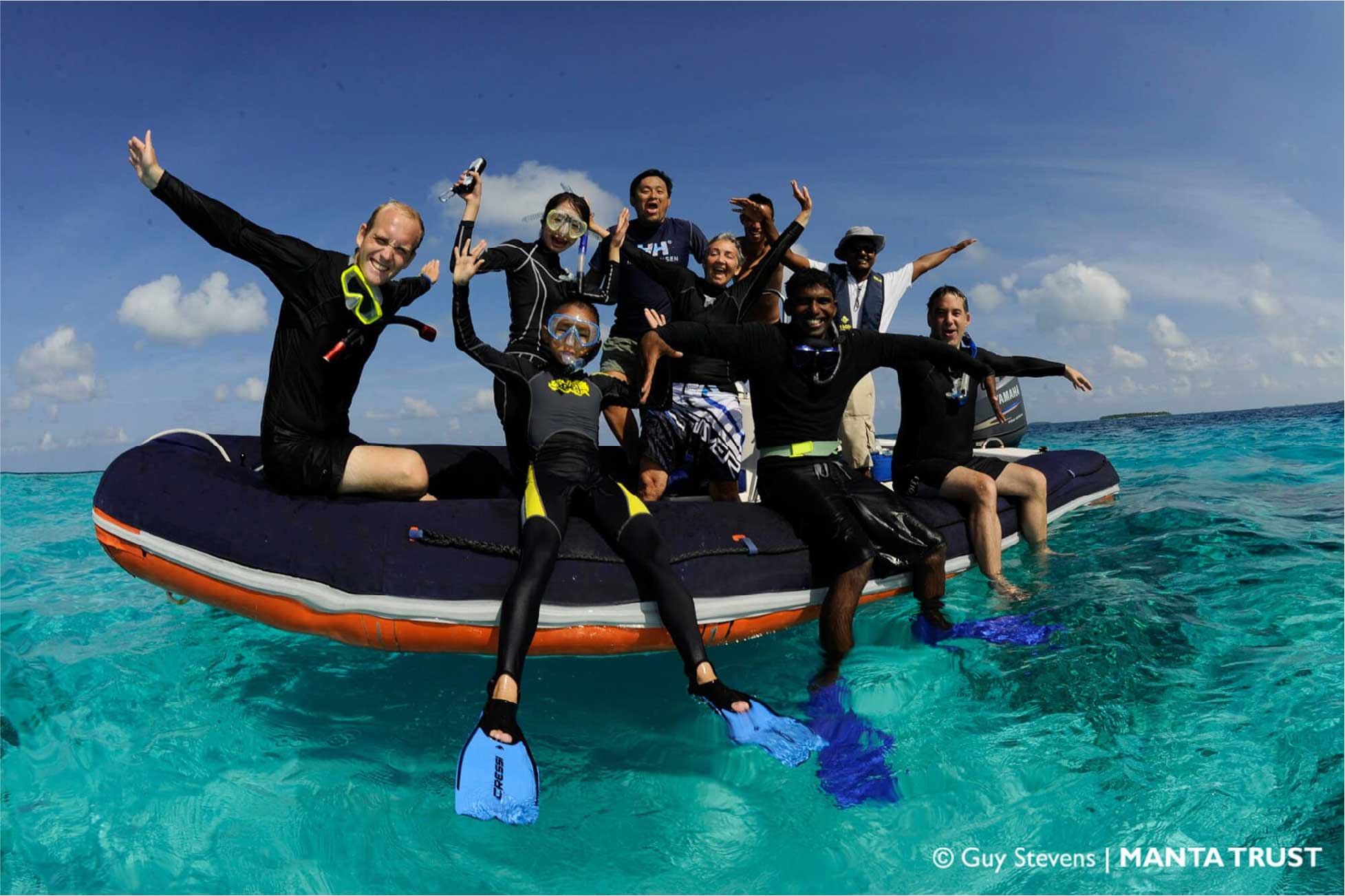 Bualume crew and guests smiling from a tender in clear turquoise water