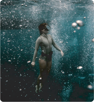 A guest floating underwater surrounded by rising bubbles