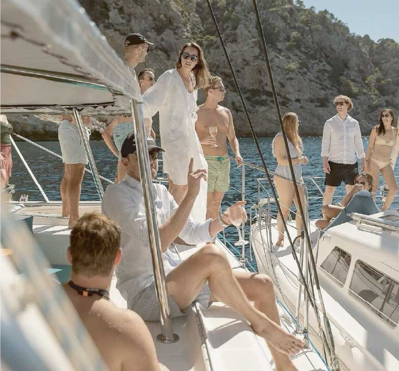 Guests gathering on a yacht deck in bright coastal sunlight